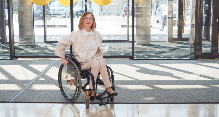 Frau im Rollstuhl auf Eingangsmatte vor Eingang